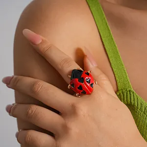 Dettaglio macro di anello coccinella rossa con cuori neri indossato da una modella