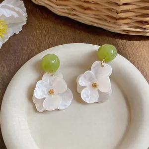 Detail view of resin flower earrings with green beads and white petals