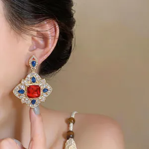 Détail des boucles d'oreilles carrées en pierre rouge de style vintage avec des strass