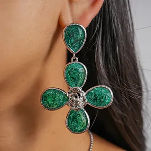 Detail shot of a large green resin four-leaf flower earring with silver texture