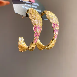 Detailed macro view of elegant C-shaped hoop earrings with pink and white zircons.