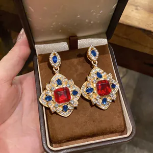 Vue détaillée de boucles d'oreilles vintage avec cristaux rouges et bleus en écrin.