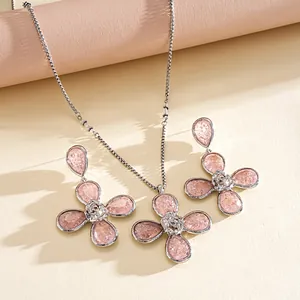 Close-up of pink resin flower necklace and earring set with silver details.