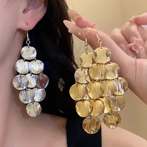 Close-up of elegant gold and silver multi-disc geometric drop earrings with metal texture