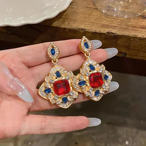 Détail de boucles d'oreilles vintage avec pierres précieuses rouges, bleues et cristaux