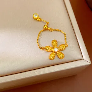 Détail d'une bague à chaîne réglable dorée avec un charm de fleur en cristal brillant