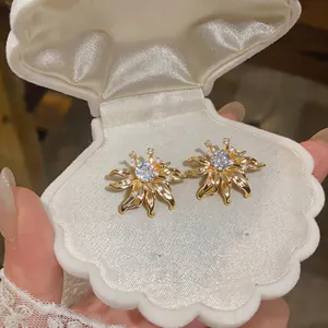 Detailed view of elegant vintage gold sunflower stud earrings inside a shell jewelry box