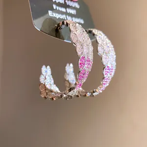 Close-up of elegant C-shaped hoop earrings featuring a pink gradient of pavé-set zircons