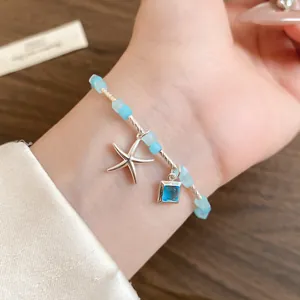 Détail d'un bracelet en perles bleu clair avec pendentifs étoile de mer et gemme carrée