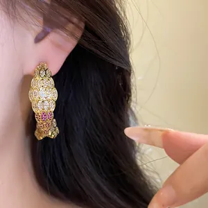 Detailed view of vintage C-shaped gold earrings with sparkling pavé zircons worn on ear
