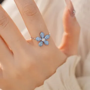 Vue détaillée en gros plan d'une bague ajustable en chaîne avec une fleur bleue.