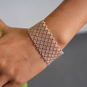 Close-up detail of a handmade geometric glass beaded cuff bracelet in white and rose gold.
