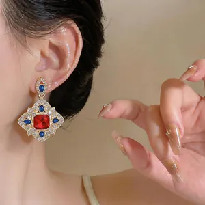 Vue détaillée de boucles d'oreilles de style cour vintage avec pierres rouges et bleues.