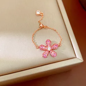 Gros plan d'une bague ajustable en or rose avec une fleur en cristaux roses pavés.