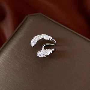 Detail view of a silver double-leaf ear cuff without piercing on a brown gift box.