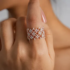 Detailed close-up showing the intricate geometric pattern of a handmade white and rose gold beaded ring