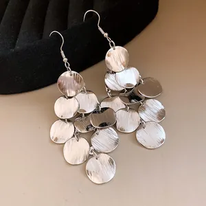 Close-up of silver-colored layered round disc tassel earrings with textured finish
