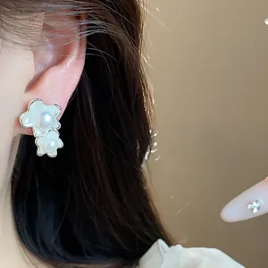 Primo piano di eleganti orecchini asimmetrici a fiore con perle indossati