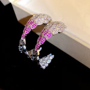 Detailed close-up of vintage C-shaped wing earrings with pink and white cubic zirconia