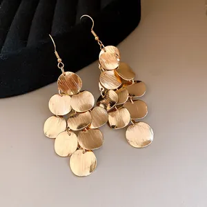 Detailed view of gold brushed metallic disc tassel drop earrings with hook design