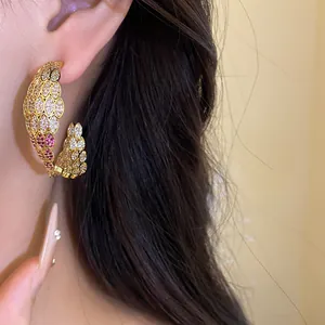 Vintage C-shaped zircon earrings in gold finish with elegant scale detail macro view