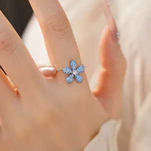 Vue détaillée d'une bague chaîne réglable en argent avec fleur sertie de pierres bleues