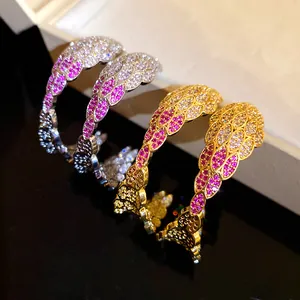 Close-up detail of C-shaped wing earrings encrusted with pink and clear zirconia stones