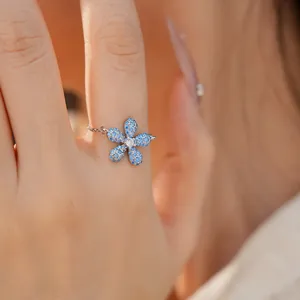 Détail d'une bague chaîne ajustable avec fleur en pavé bleu pour un look estival