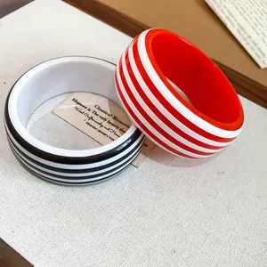 Macro view of minimalist red and black striped resin bangles showing smooth finish and texture