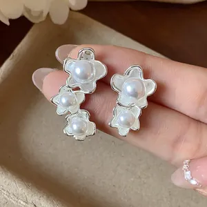 Primo piano di orecchini asimmetrici in argento con delicate perle a fiore