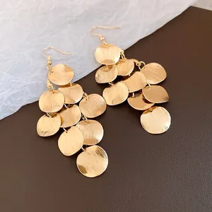Macro detail of retro gold multi-disc drop earrings featuring a brushed metal texture