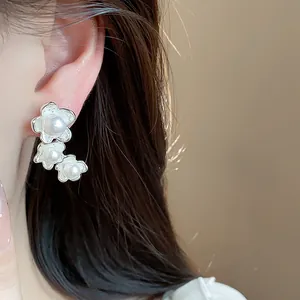 Primo piano di eleganti orecchini asimmetrici a fiore con perle stile francese.