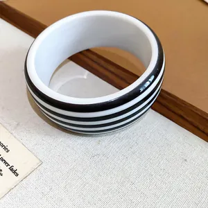 Close-up detail of a modern black and white striped resin bangle with a smooth finish.