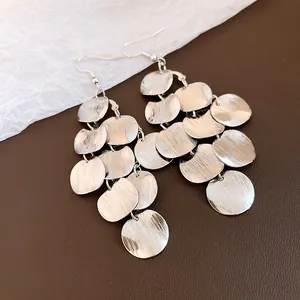 Close-up of silver-finished round geometric tassel earrings with textured surface