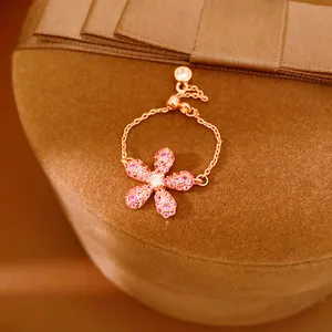 Gros plan élégant d'une bague fleur en cristal rose avec chaîne réglable en or rose.