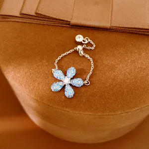 Gros plan d'une bague chaîne réglable avec fleur en cristaux bleus