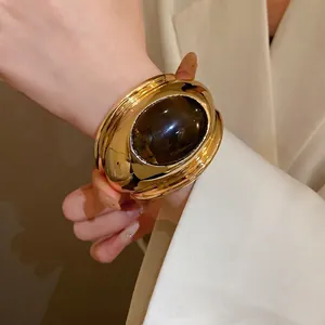 Vintage gold oval cuff bracelet featuring a large brown tiger eye stone on wrist.