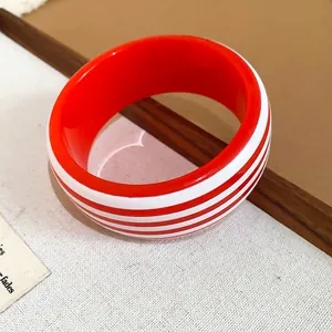 Detailed macro shot of a chic red and white striped resin bangle on elegant background.