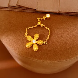 Gros plan d'une bague chaîne fleur en or avec cristaux sur support en velours.