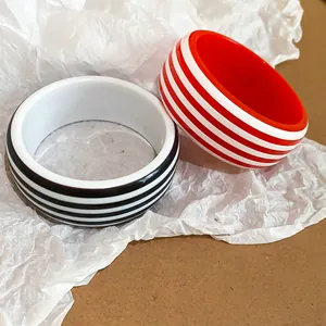 Detailed close-up showing red and black striped resin bracelets on white paper background