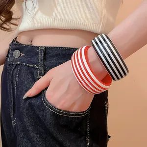 Detail view of stylish red and black striped resin bangles worn on a model's wrist