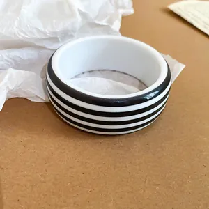 Close-up of black and white striped resin bangle bracelet on paper