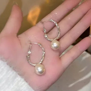 Elegant French style textured silver hoop earrings with round white pearls held in palm
