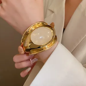 Close-up detail of a vintage gold oval open cuff bracelet with a translucent quartz stone