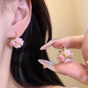 Gros plan de boucles d'oreilles en résine rose avec strass brillants et monture dorée.