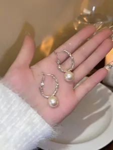 Close-up of French style silver hoop earrings with elegant hanging white pearls