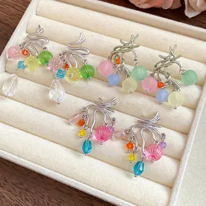 Dettaglio di orecchini colorati in resina e perle di vetro in un vassoio di velluto