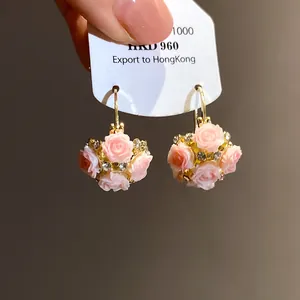Gros plan de boucles d'oreilles créoles roses en résine avec strass sur carte blanche