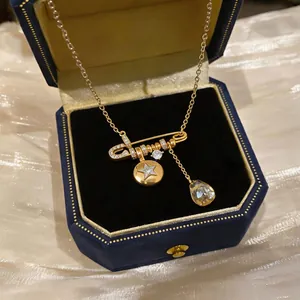 Close-up of 18K gold-plated safety pin necklace with star and teardrop zircon pendants