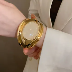 Detail view of a vintage gold cuff bracelet with a large oval stone inlay on model